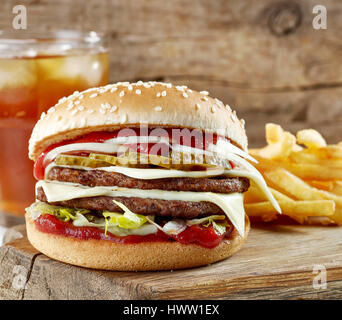fresh tasty burger and potatoes on wooden cutting board Stock Photo
