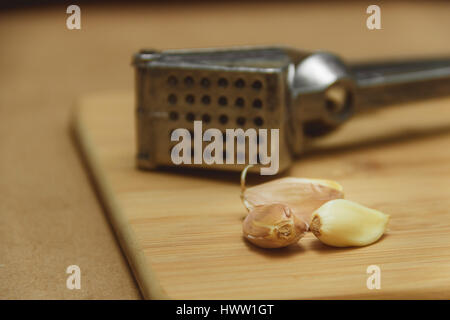 closeup garlic and garlic press on cutting board. Stock Photo