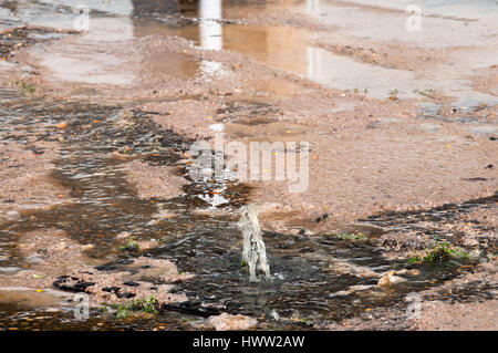 water damage to road from burst leaking water pipe Stock Photo