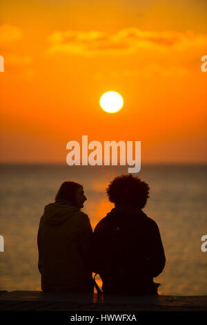 Aberystwyth Wales UK, Thursday 23 March 2017 UK Weather: A couple sit and watch the spectacular sunset over Cardigan Bay in Aberystwyth on the west Wales coast Photo Credit: Keith Morris/Alamy Live News Stock Photo