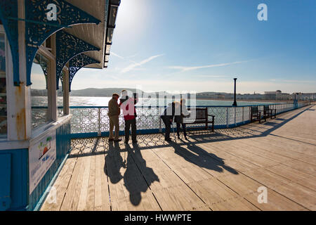 North Wales, UK 24th March 2017, Forecasters predict a high over the UK this weekend with blue sky and warmer temperatures but cold by night. Visitors to Llandudno Pier enjoying the warmer conditions and finding time for a photograph of the seafront © DGDImages/Alamy Live News Stock Photo
