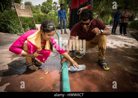 People are collecting water at a broken garden hose at one of the most famous tourist attraction points in India, at the Tadsch Mahal. Stock Photo