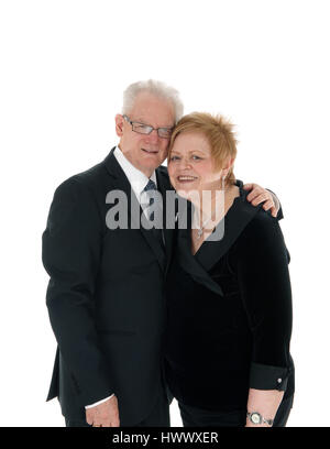A beautiful senior citizen couple standing and embracing each other in suits, isolated for white background. Stock Photo