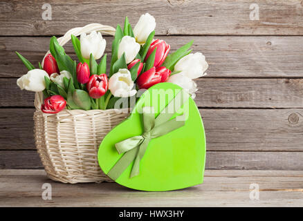 Colorful tulips bouquet and gift box in front of wooden wall. Red and white. With space for your greetings Stock Photo