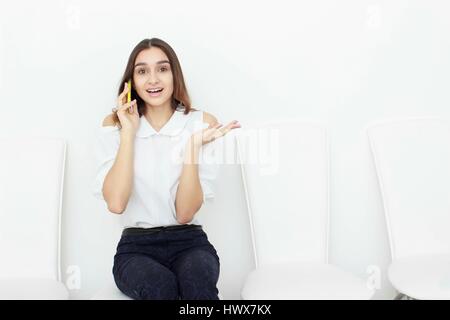 Young business woman sitting on chair and using mobile phone Stock Photo