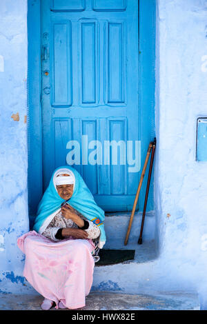 Chefchaouen, Morocco.  Old Berber Woman in Traditional Clothing Sitting on her Doorstep. Stock Photo