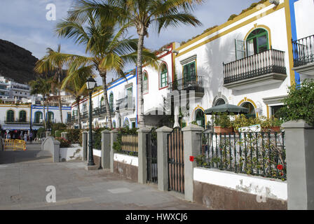 White houses, palms, flowers blossom in the evening time. Street view, Puerto de Mogan, Gran Canaria, Spain. Stock Photo