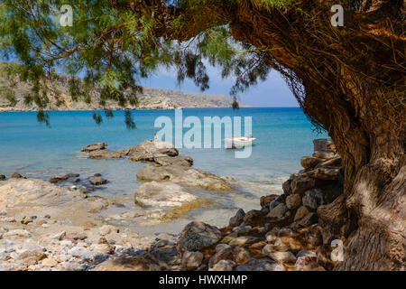 small boat is tied with a rope to the rock on a small beach in the summer on the island of Creta Greece Stock Photo