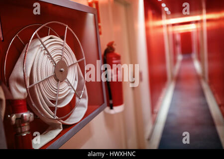 Fire extinguisher and fire hose reel in hotel corridor Stock Photo