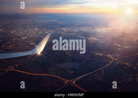 View from a landing airplane out the window of city at sunset Stock Photo