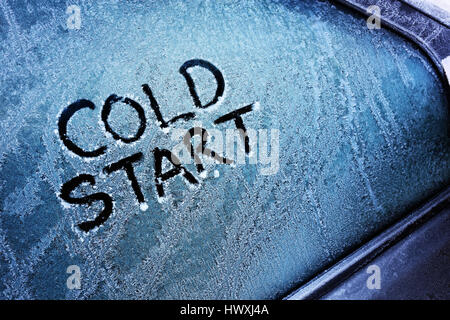 Cold start message written on frozen car windshield window Stock Photo