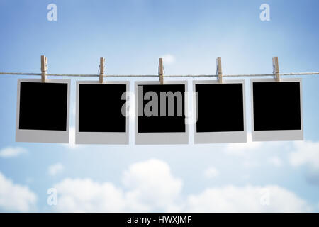 Blank instant print transfer photographs hanging on a clothesline in front of a blue sky Stock Photo