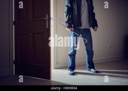 Burglar committing a burglary crime in a house with a crowbar Stock Photo