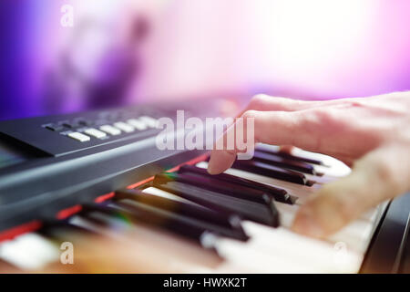 Pianist musician performing live playing keyboard in a band with saxophone player in background Stock Photo