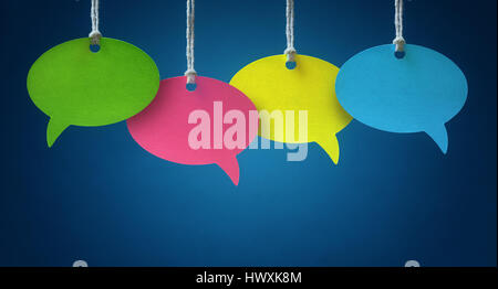 Blank colorful speech bubbles hanging from a cord over blue background Stock Photo