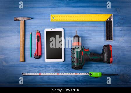 Tinker toools on the green wooden surface, and tablet to display web site. DIY concept. Stock Photo