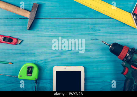 Tinker toools on the green wooden surface, and tablet to display web site. DIY concept. Stock Photo