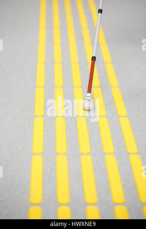 Blind pedestrian walking and detecting markings on tactile paving with textured ground surface indicators for blind and visually impaired. Blindness a Stock Photo