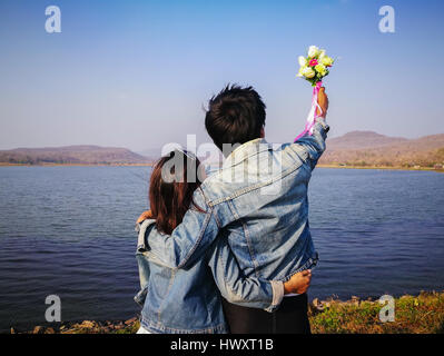 back view couples in jeans jecket standing happy cliffside looking sea view, Kalasin Thailand Stock Photo