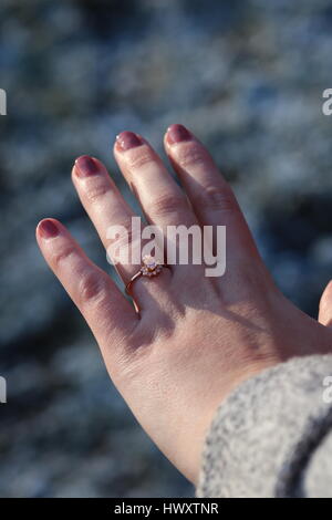Rose Gold engagement ring on a lady's hand with pink painted nails Stock Photo