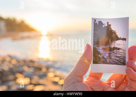 Spain, Costa Brava, Lloret de Mar, woman's hand holding instant photo of Castillo de los Plaja near by Stock Photo