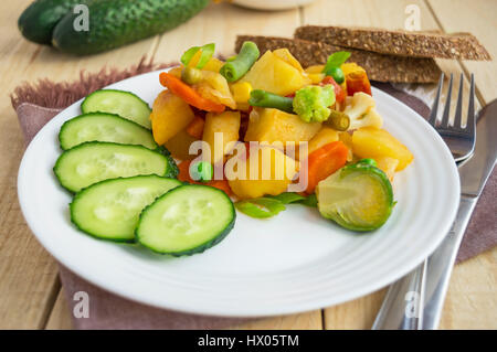 Vegetable stew (potatoes, asparagus, carrots, Brussels sprouts, corn, peas, savoy cabbage, broccoli) in a white plate. Vegan. Stock Photo