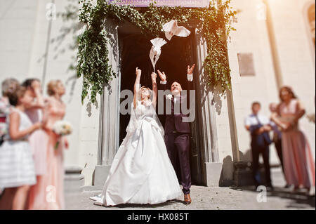 Wedding couple with releasing doves into the sky against church gate. Stock Photo