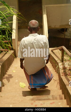 Sri Lankan man walking down temple stairs Stock Photo