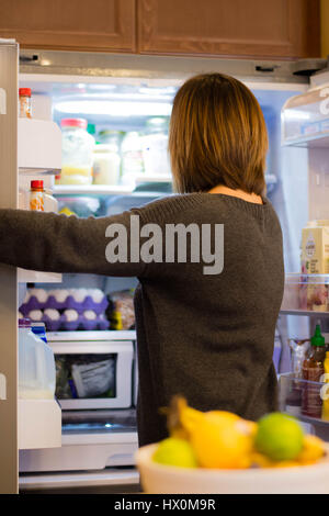 Female reaching into french door refrigerator. Stock Photo