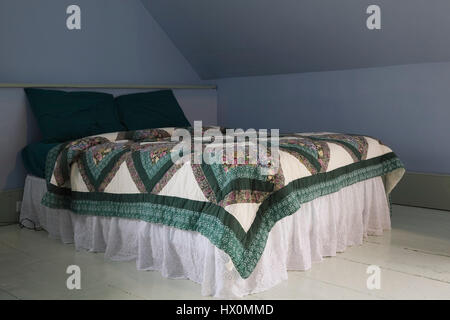 Double bed with bedspread  in blue attic bedroom of 1850 old house interior. Stock Photo