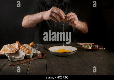 Man hands cracking an egg on a black background Stock Photo