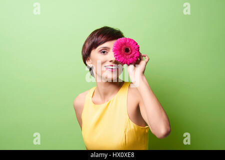 Female model covering eye with flower Stock Photo
