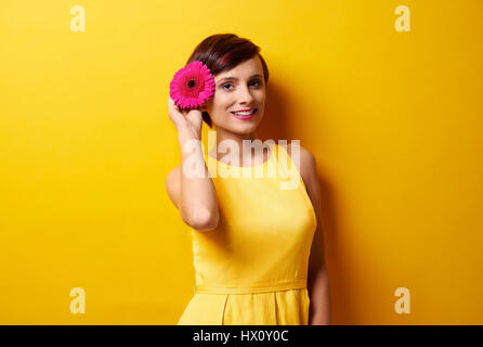 Picture of model holding flower next to ear Stock Photo