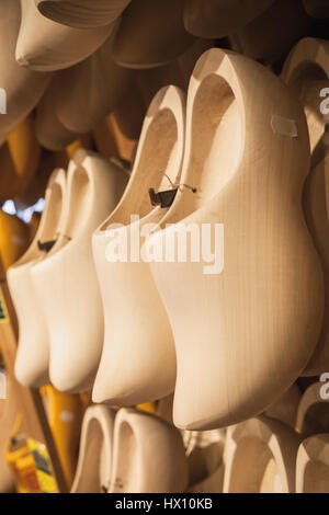 Uncolored clogs made of poplar wood. Klompen, traditional Dutch shoes for everyday use hang in souvenir shop Stock Photo
