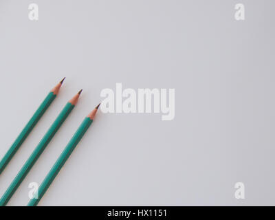 Three identical pencils lying on a plain background. Stock Photo