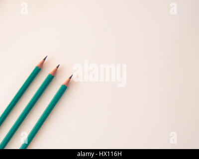 Three identical pencils lying on a plain background. Stock Photo