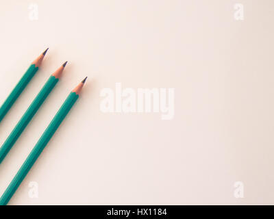 Three identical pencils lying on a plain background. Stock Photo