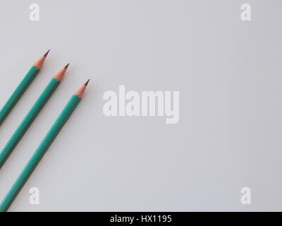 Three identical pencils lying on a plain background. Stock Photo