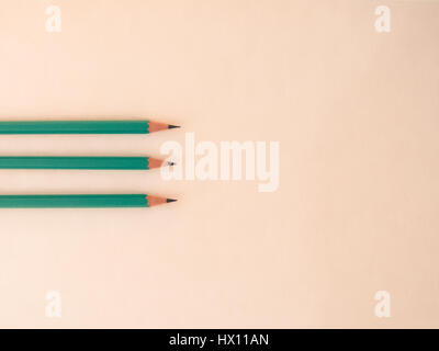 Three identical pencils lying on a plain background. Stock Photo