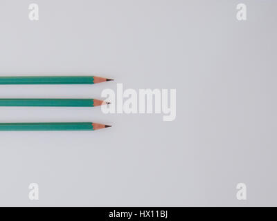Three identical pencils lying on a plain background. Stock Photo