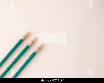 Three identical pencils lying on a plain background. (Rubbers) Stock Photo