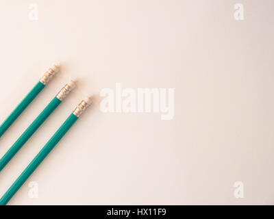 Three identical pencils lying on a plain background. (Rubbers) Stock Photo
