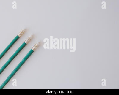 Three identical pencils lying on a plain background. (Rubbers) Stock Photo