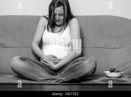 Intimate portrait of young pregnant woman holding her belly. Stock Photo