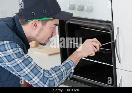 young repairman in overall installing brand new oven in kitchen Stock Photo