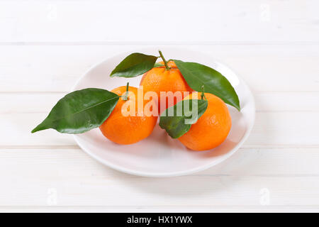 plate of fresh tangerines with leaves on white background Stock Photo