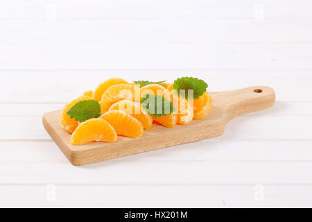 pile of fresh tangerine slices on wooden cutting board Stock Photo