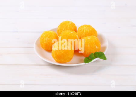 plate of whole and peeled oranges on white background Stock Photo