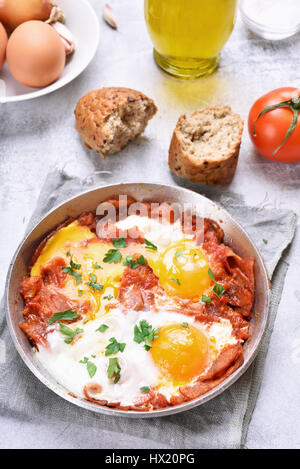 Fried eggs with tomato and bacon in frying pan Stock Photo
