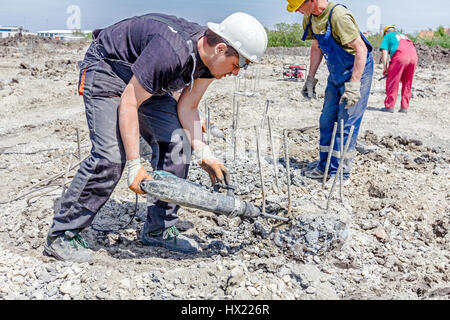 Zrenjanin, Vojvodina, Serbia - April 30, 2015: Constructions workers are using jackhammer to realign reinforced pillars in the ground. Stock Photo